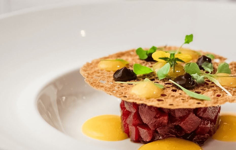 Plato de atún con crujiente, hierbas frescas y salsas por encima.